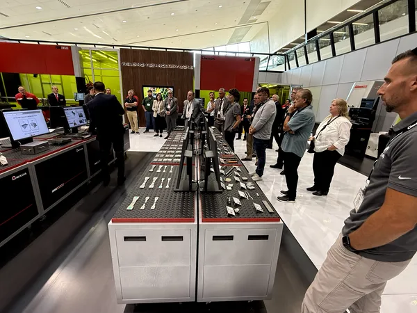 Visitantes revisando piezas de muestra soldadas en la mesa de exhibición